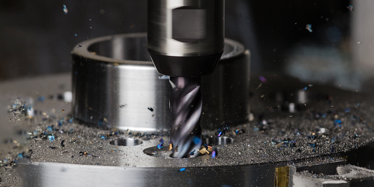 Close-up of CNC end mill cutting a metal workpiece, with metal chips scattered around the cutting area