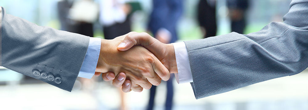 Two businesspeople shaking hands in a professional setting with blurred office background