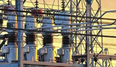 High-voltage electrical substation with ceramic insulators and power lines at sunset