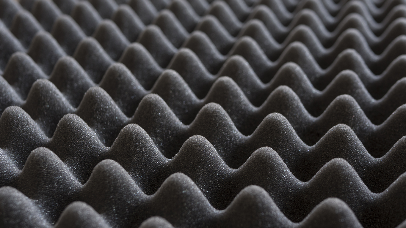 Close-up of gray soundproof foam with egg-crate texture, repeating ridges and valleys for acoustic insulation