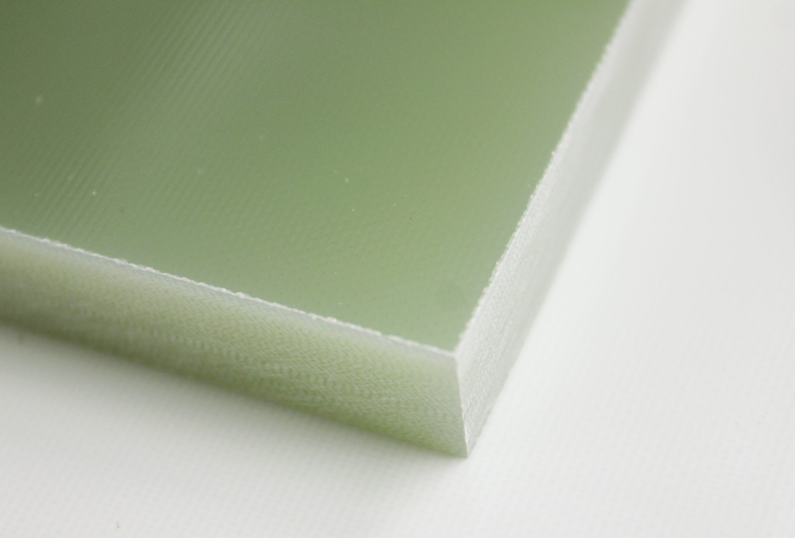 Close-up corner of green G10/FR4 fiberglass epoxy laminate sheet showing smooth surface and cut edge