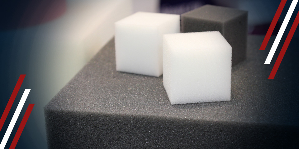White and gray foam cubes on a large dark foam block, comparing foam types and densities