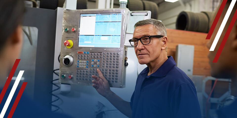 Technician operating CNC machine control panel, pointing at keypad and screen in a manufacturing workshop