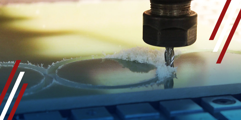 Close-up of a CNC milling cutter machining circular cavities, with plastic shavings and machine bed in the foreground