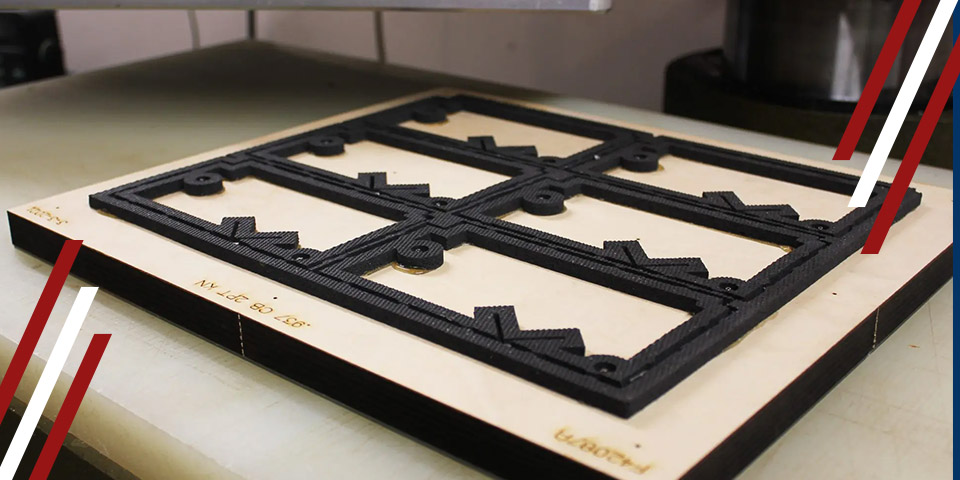 Die-cutting tool on a worktable, showing a black metal cutting die mounted on a wooden board for automated production