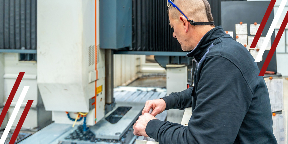 Technician inspecting CNC machine in workshop, checking components near the cutting bed during troubleshooting