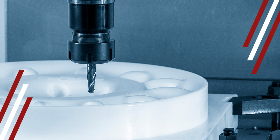 CNC milling cutter machining a white plastic part with multiple recessed cavities on a worktable