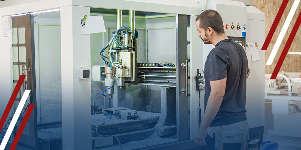 Technician operating a CNC milling machine behind safety enclosure in an industrial workshop