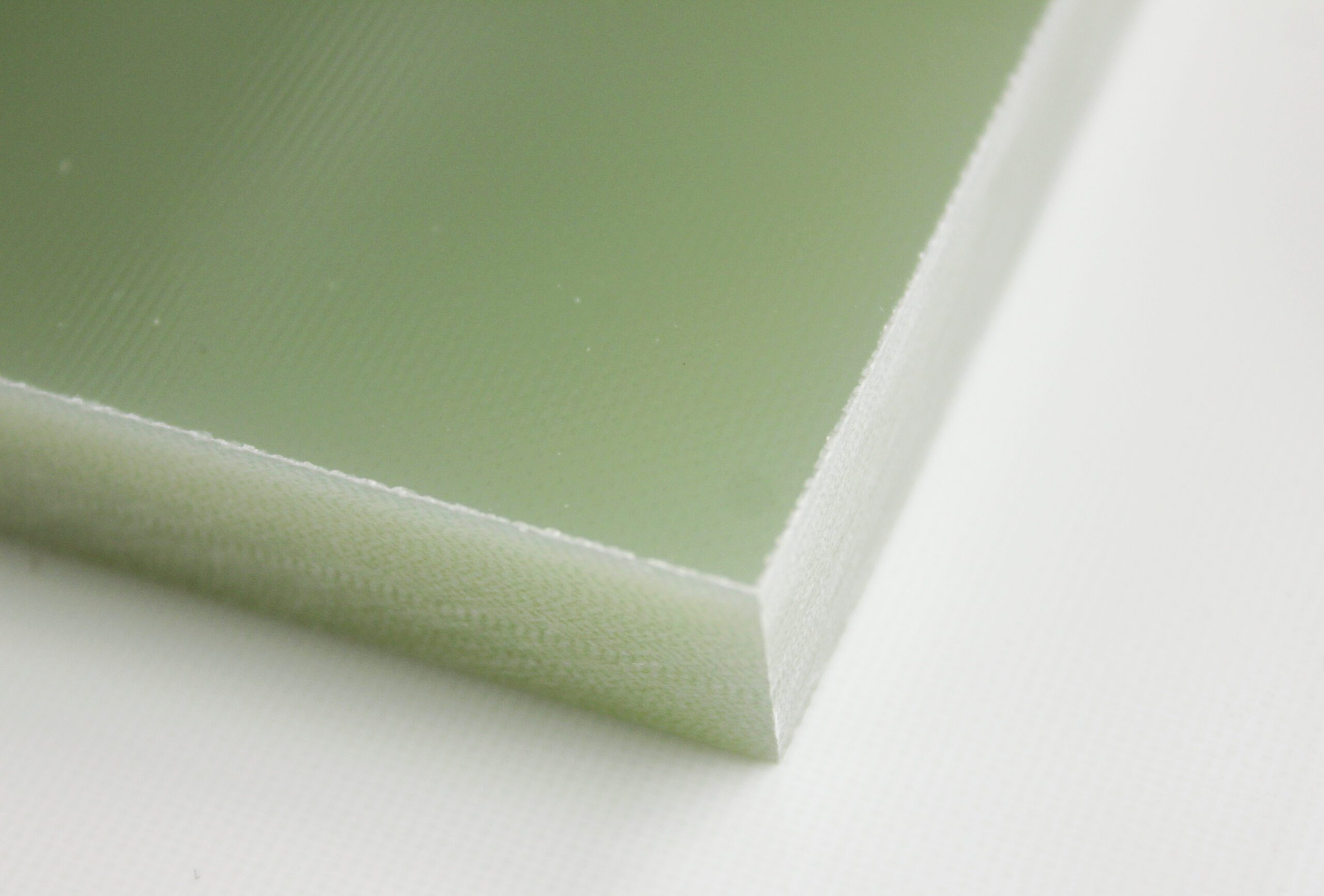 Close-up of a green fiberglass laminate sheet corner, showing smooth surface texture and white beveled edge