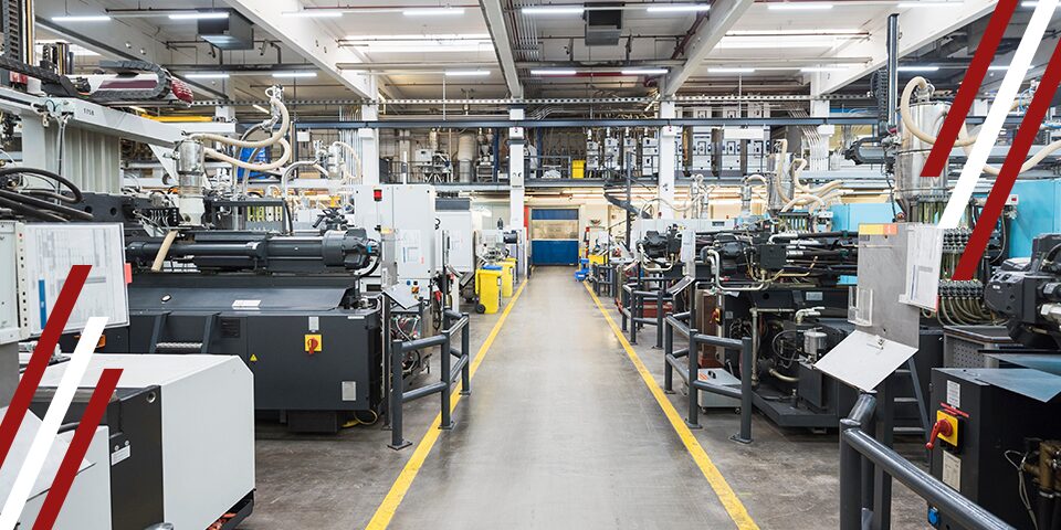 Factory production line with industrial machines and piping along a central aisle marked by yellow safety lines